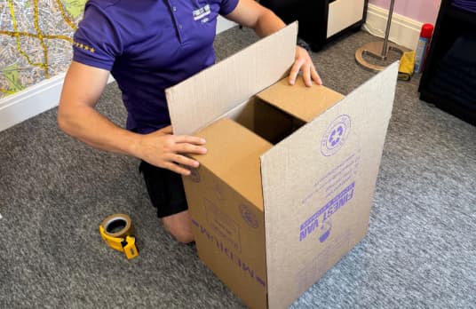 Finest Van removals specialist preparing an upside-down moving box before folding the bottom flaps