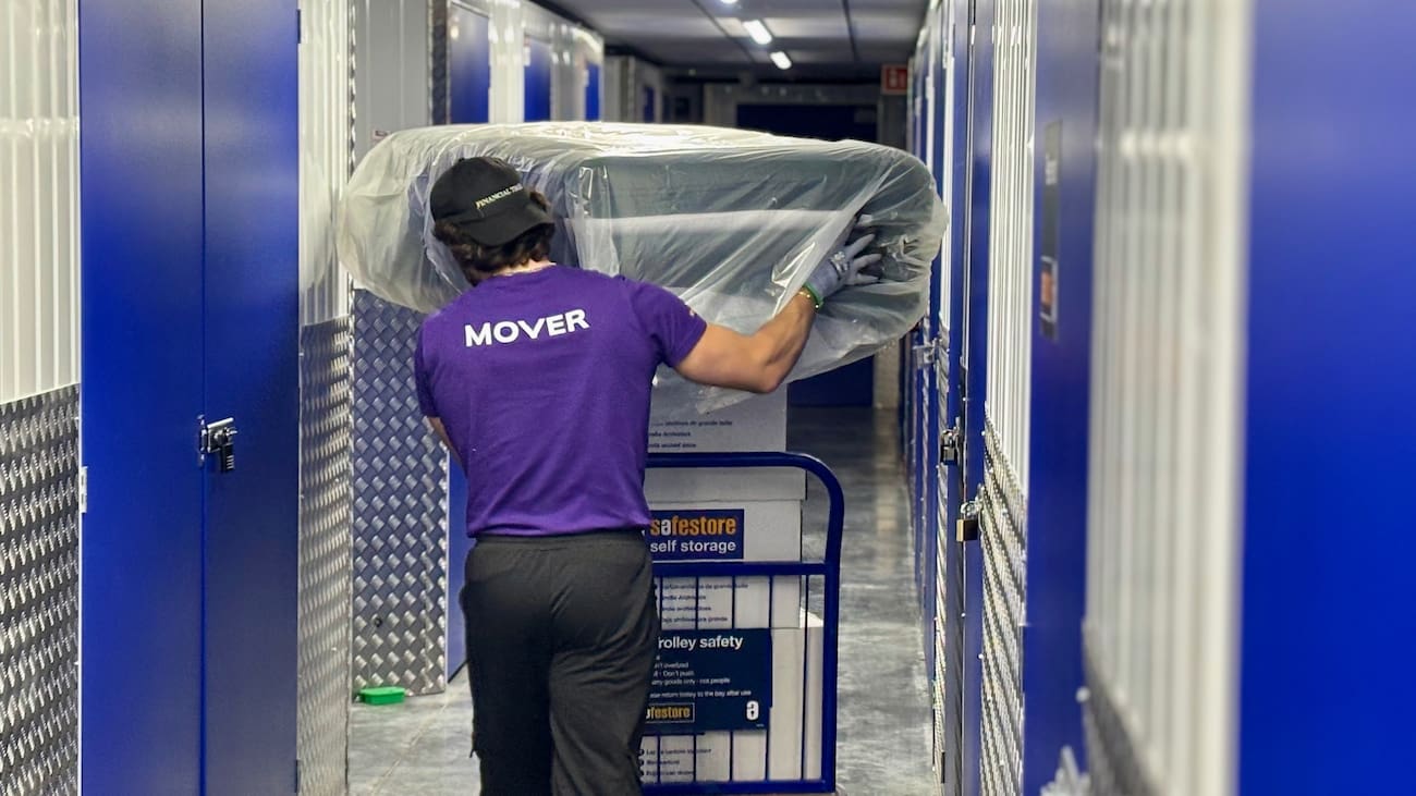 Finest Van removals specialist moving storage boxes and a protected sofa cushion inside a London storage facility