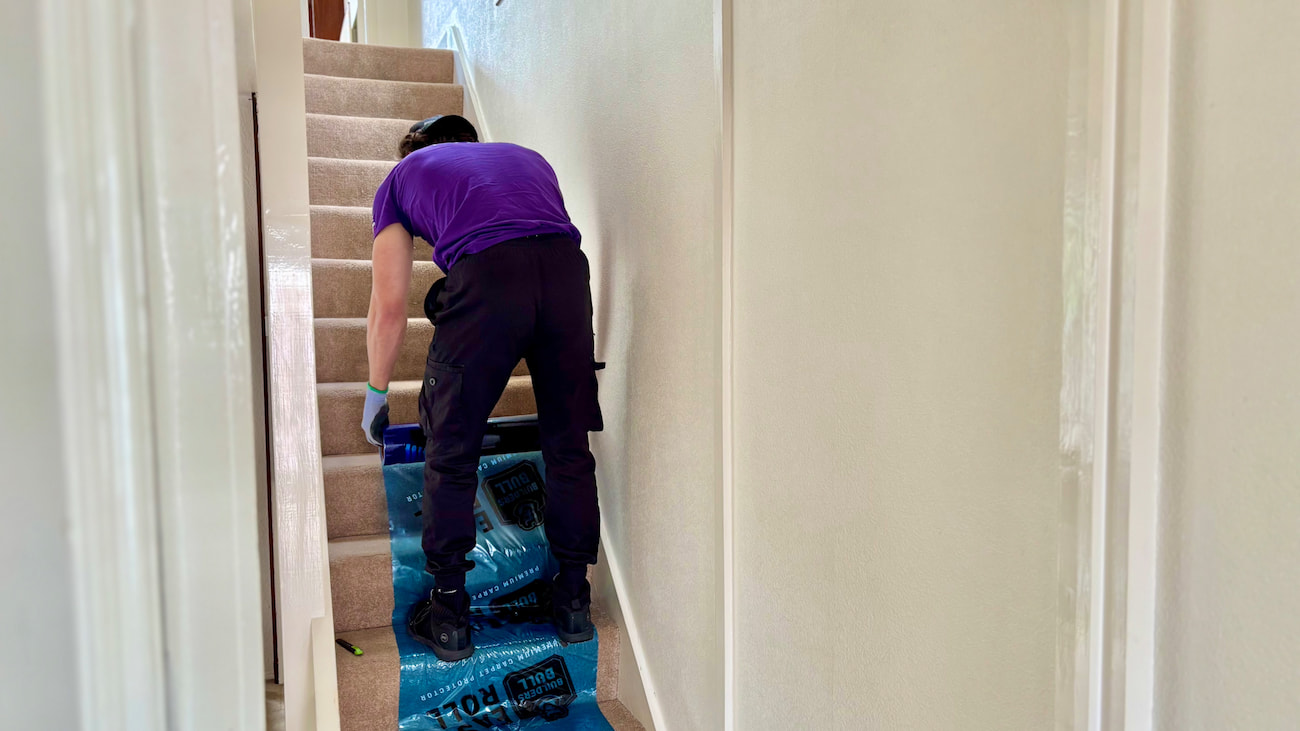 Finest Van removals specialist placing protective covering over a carpeted staircase before a house move