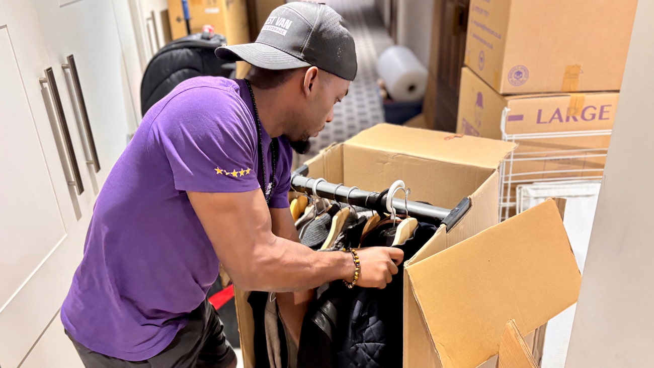 Finest Van removals specialist packing hanging clothes into a wardrobe box