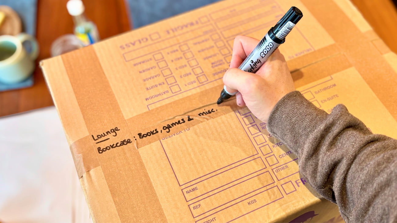 Packed moving box being labelled by a removal specialist