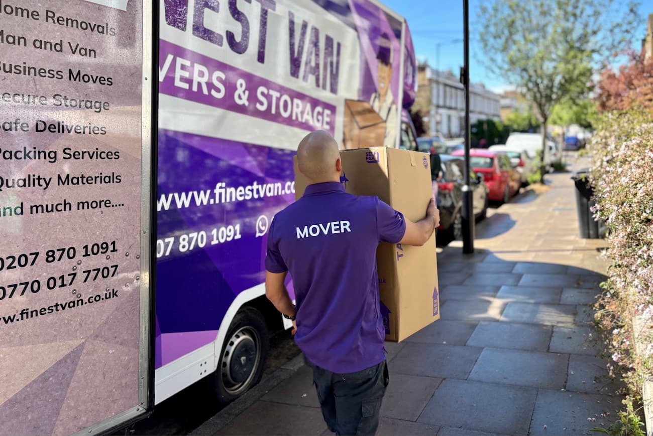 Removal specialist carrying a box during a university move in London Removal specialist carrying a moving box from a van towards a London property