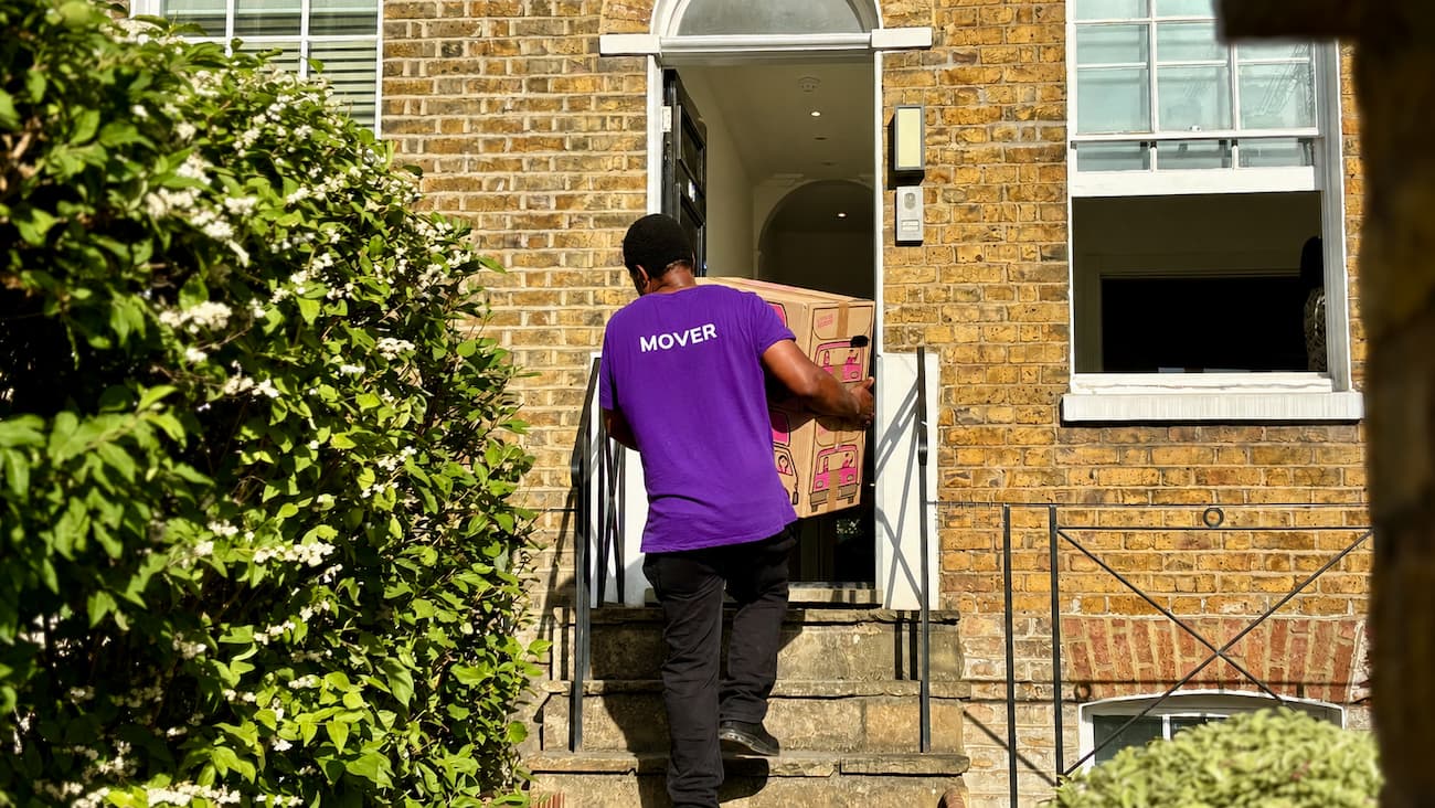 Removals specialist carrying a box into a London flat during a student move