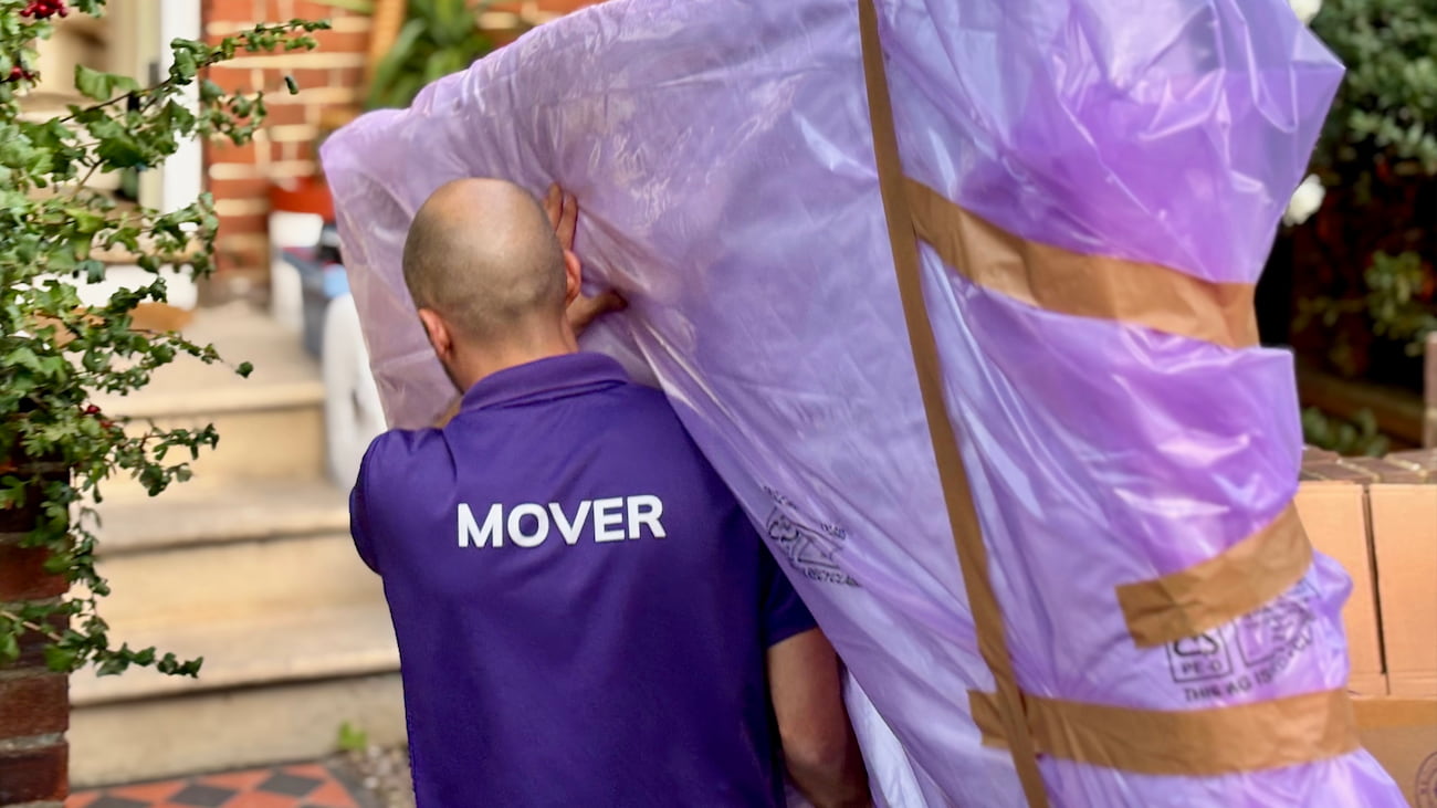 Finest Van removals specialist carrying a mattress protected in a mattress cover
